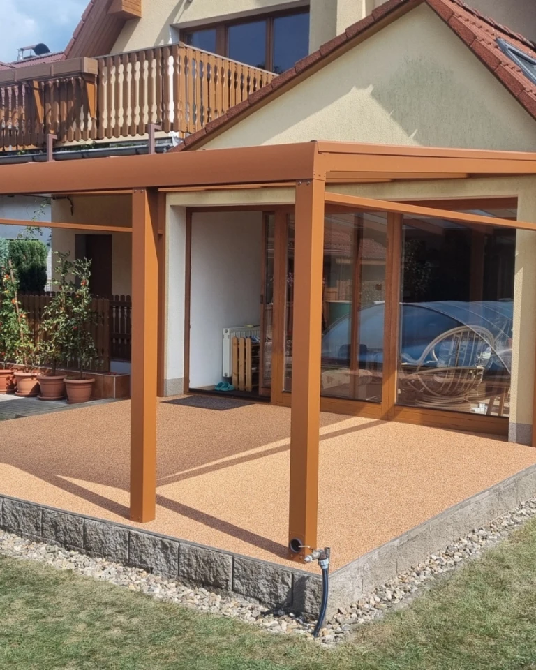 Moderná hnedá hliníková pergola so sklenenými stenami na terase rodinného domu.