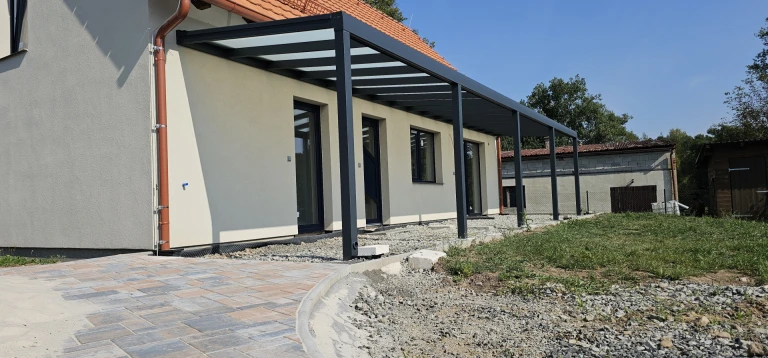 Moderná hliníková pergola ROBUST so sklenenou strechou nainštalovaná na terase rodinného domu
