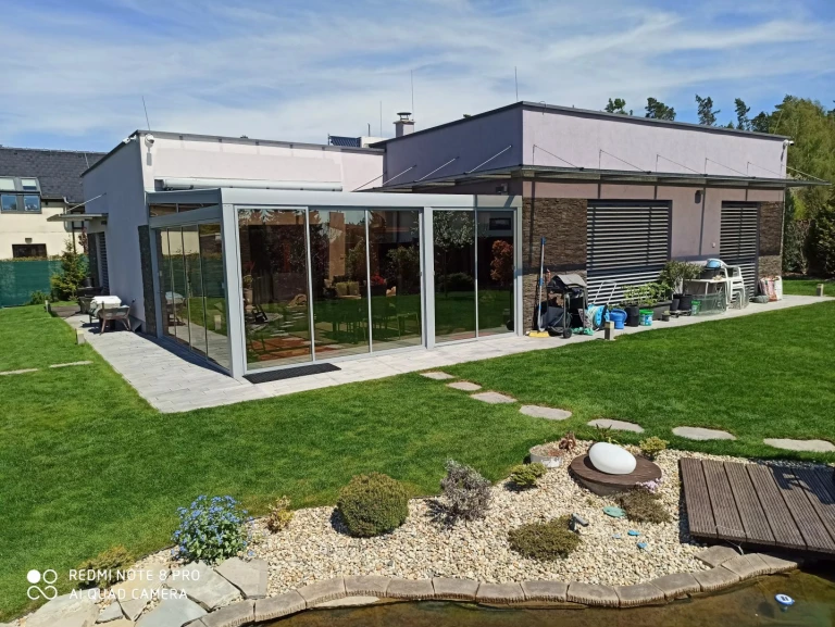 Moderná hliníková pergola so zasklením pri rodinnom dome v záhrade