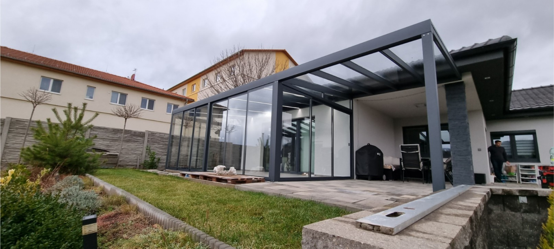 Moderná presklená hliníková pergola s antracitovou konštrukciou postavená pri rodinnom dome v Klášterci.