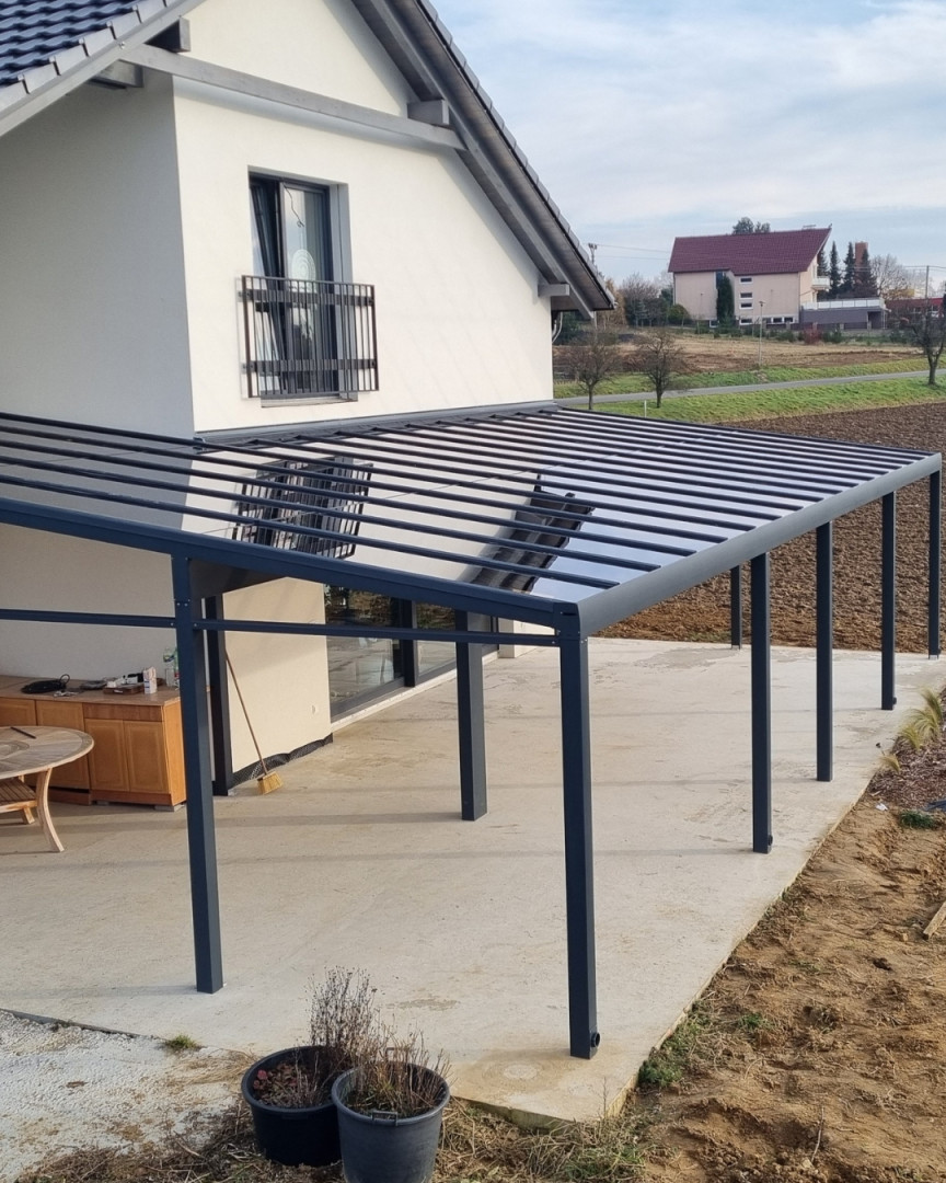 Moderná tmavosivá hliníková pergola so sklenenou strechou namontovaná k rodinnému domu v Senci.