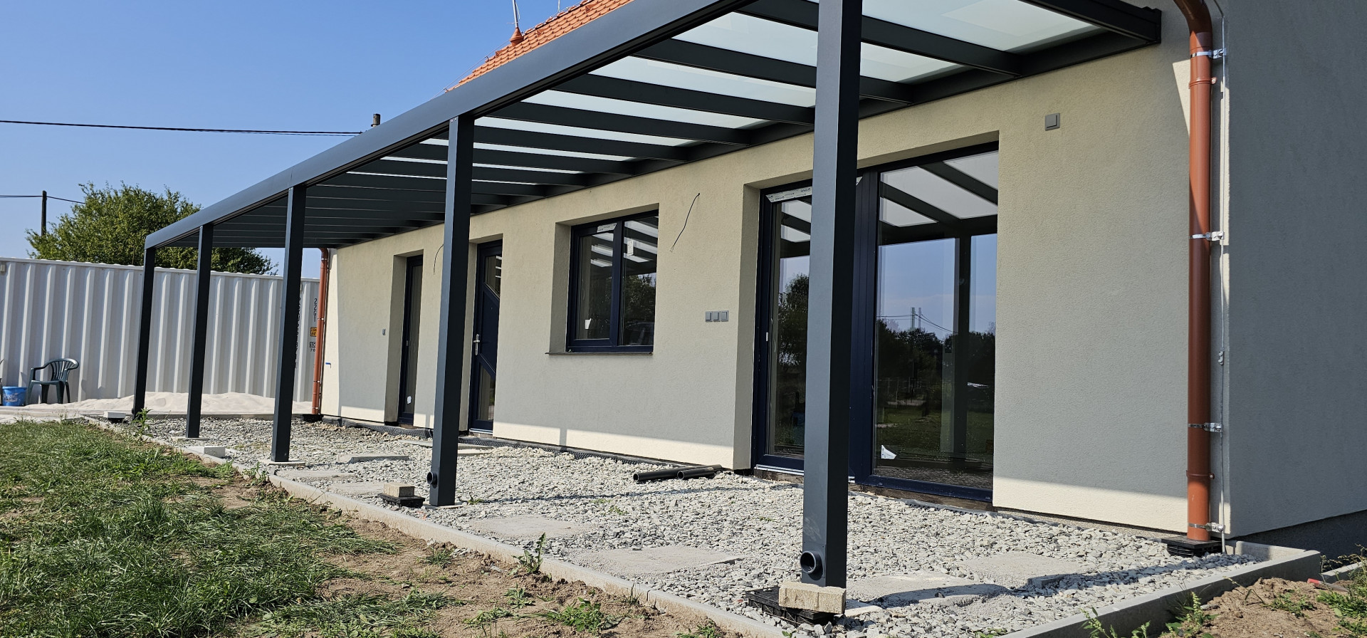 Moderná hliníková pergola so sklenenou strechou pripevnená k stene rodinného domu