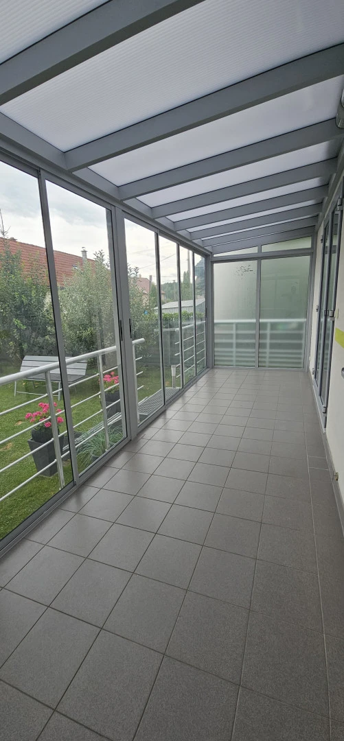 Interiér presklenej zimnej záhrady s výhľadom do zelenej záhrady