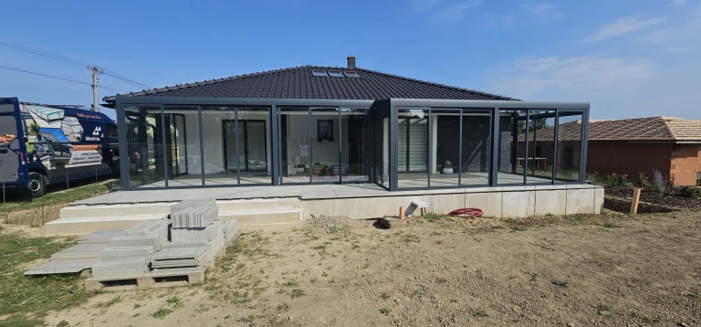 Moderná presklená zimná záhrada s antracitovou konštrukciou pripojená k rodinnému domu