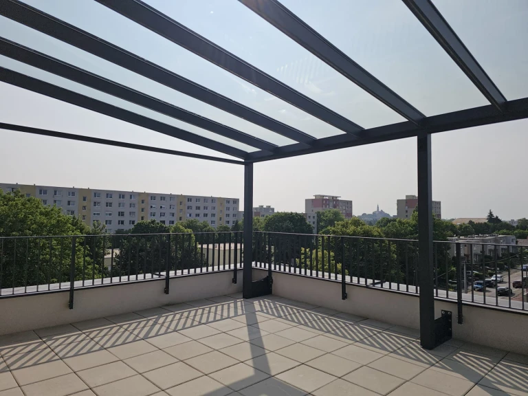 Moderná hliníková pergola so sklenenou strechou na priestrannej terase s výhľadom na mesto.