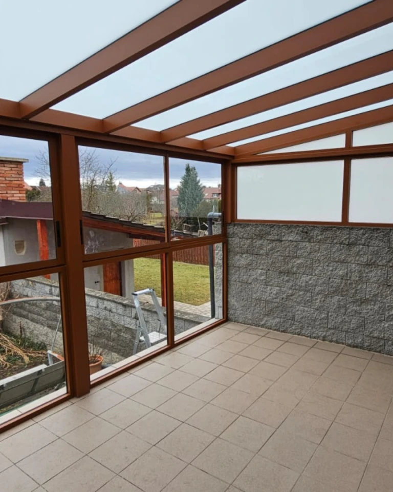 Presklená hliníková pergola s hnedou konštrukciou a výhľadom do záhrady
